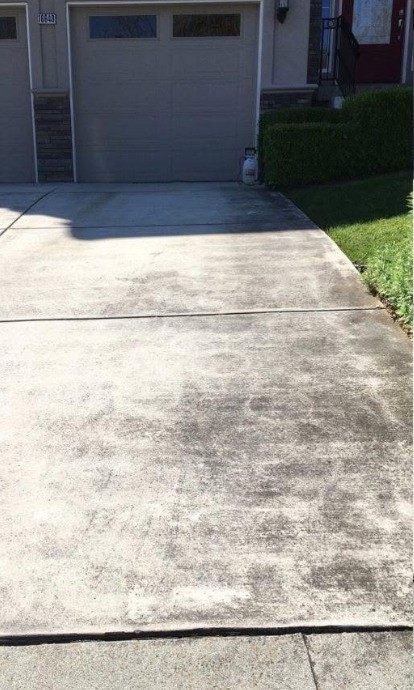 The same driveway covered in dirt and organic staining before cleaning