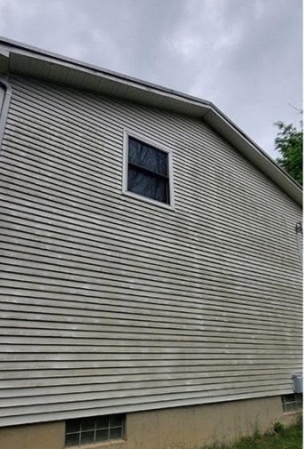 The same siding dulled by grime and organic growth before washing
